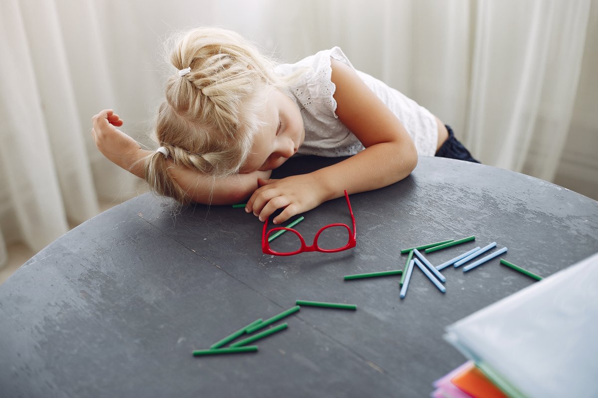 A young girl laying on the table, looking away with a distracted expression. A young girl laying on the table, looking away with a distracted expression.