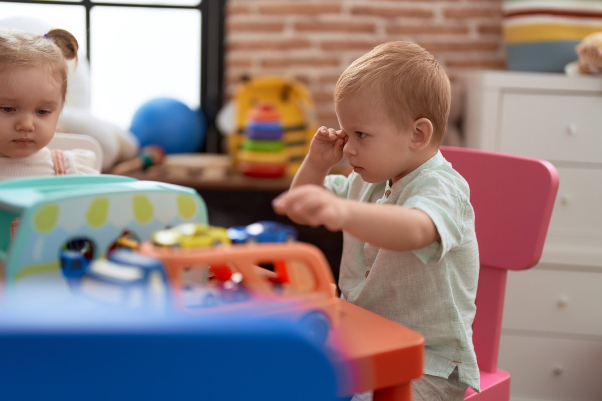 A young child playing with a toy truck at school. A young child playing with a toy truck at school.