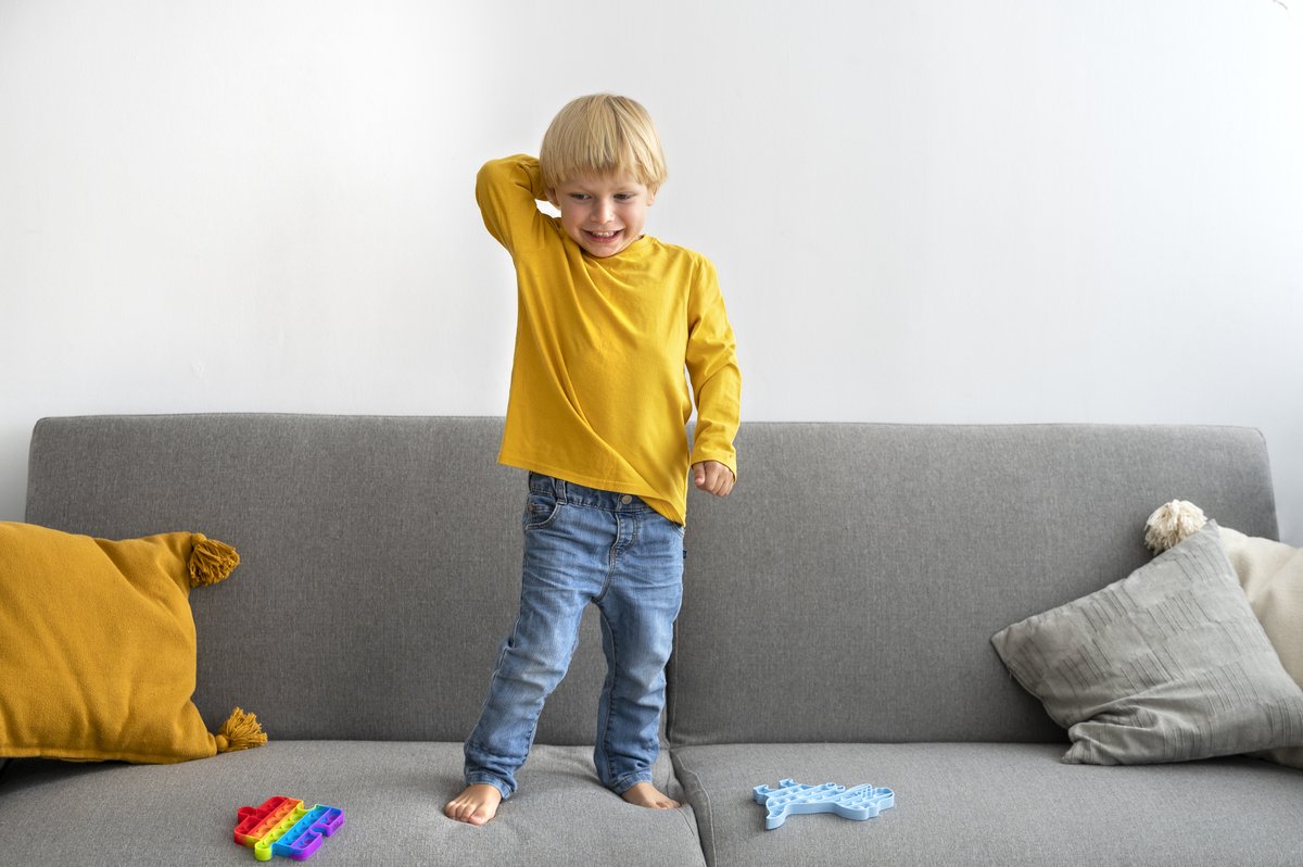 a kid smiling while standing on the couch a kid smiling while standing on the couch