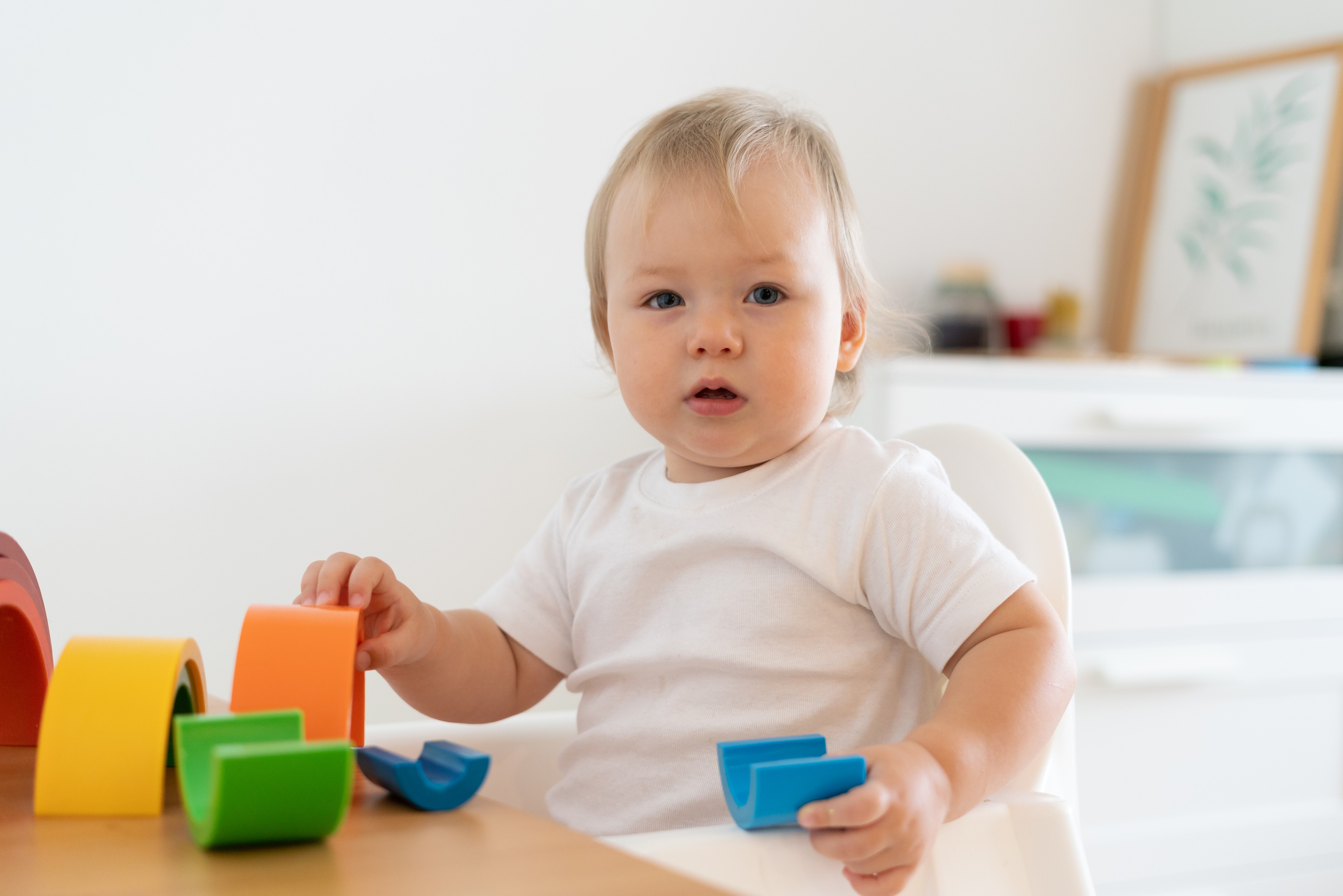 Renkli oyuncak blokları elleriyle inceleyen 6 aylık bir bebek