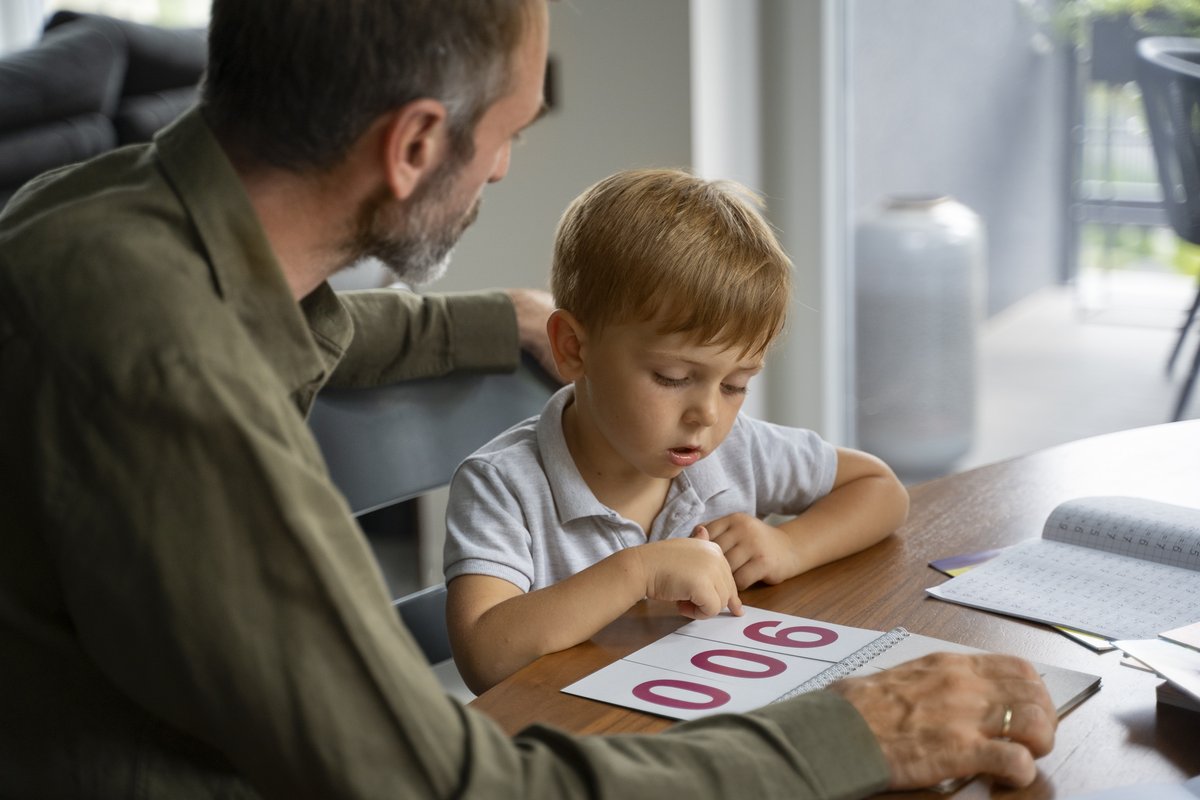 A 5-year-old boy interacting with colorful numbers at a table with a male adult A 5-year-old boy interacting with colorful numbers at a table with a male adult