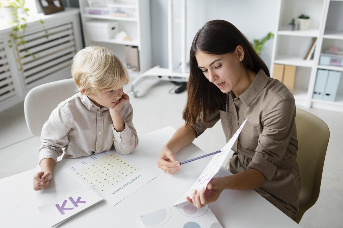 A female adult reading a book and doing an activity with a boy in a patient and loving way A female adult reading a book and doing an activity with a boy in a patient and loving way