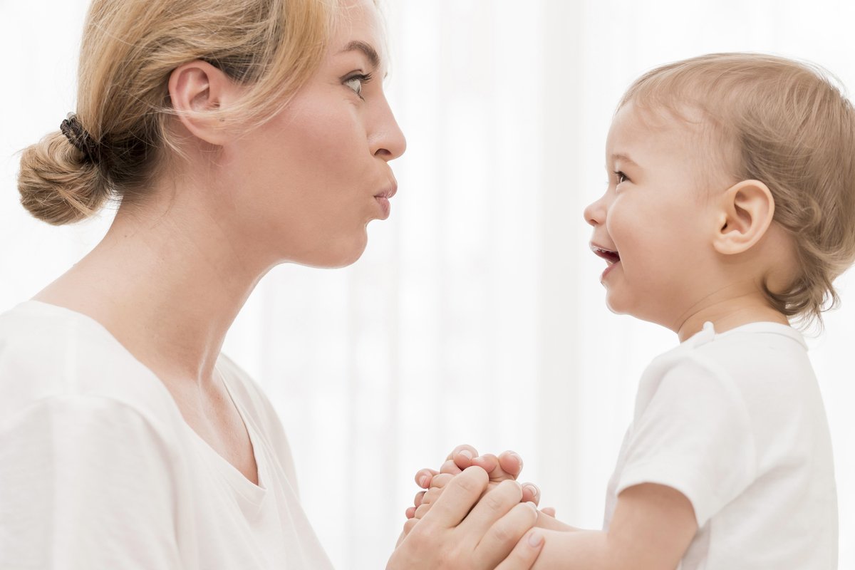 A caring parent playing on the floor with their baby, making eye contact