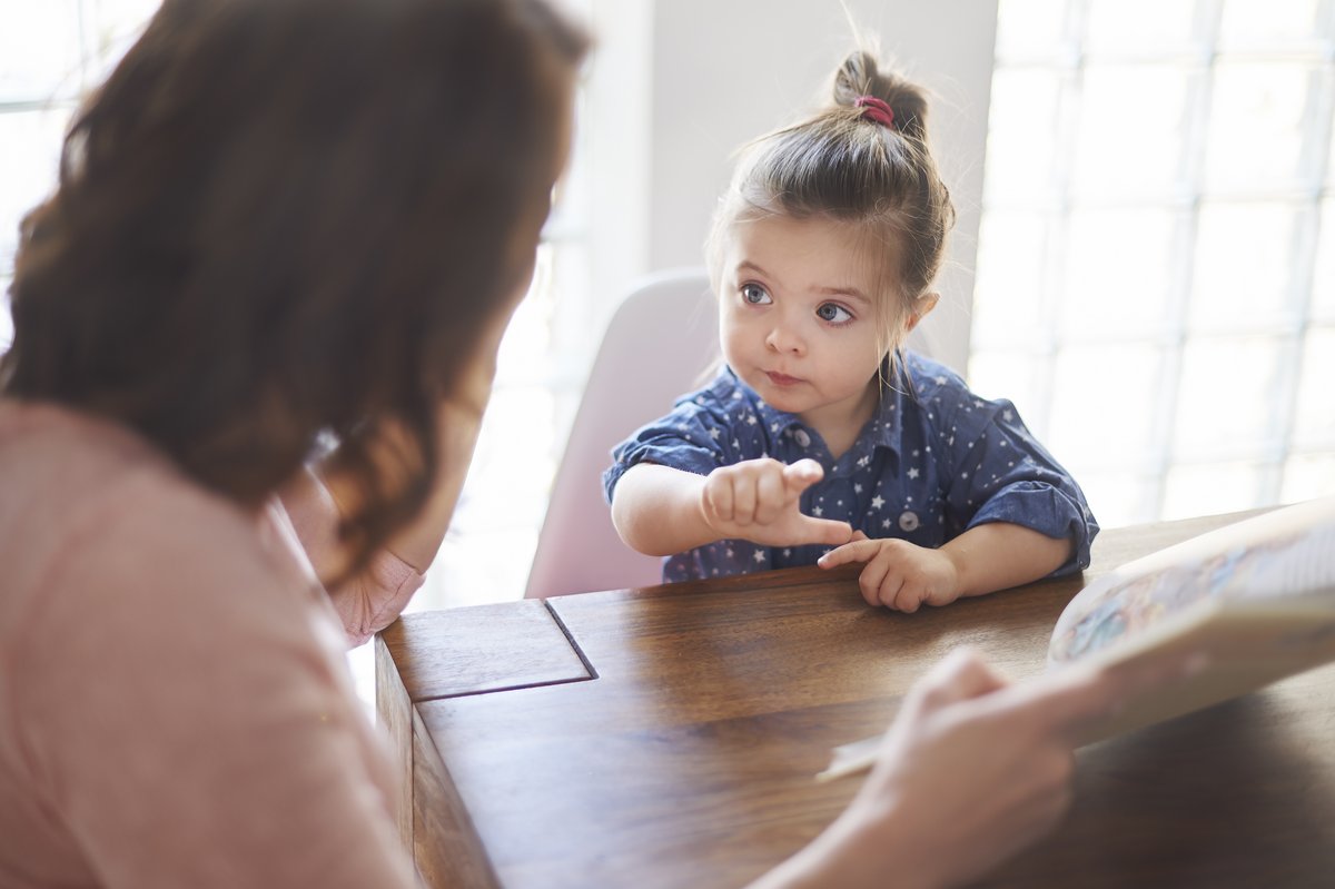 a girl and her mother communicating through shared book reading