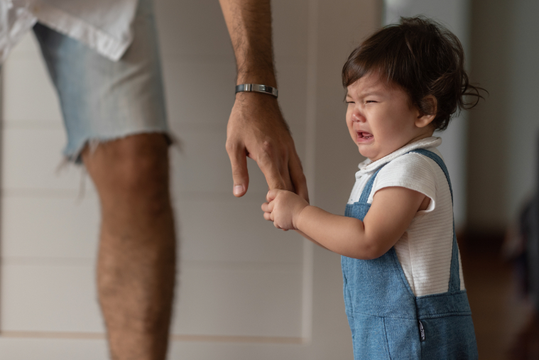 Ebeveyninin elinden tutarken ağlayan bir bebek Crying baby holding a parent's hand
